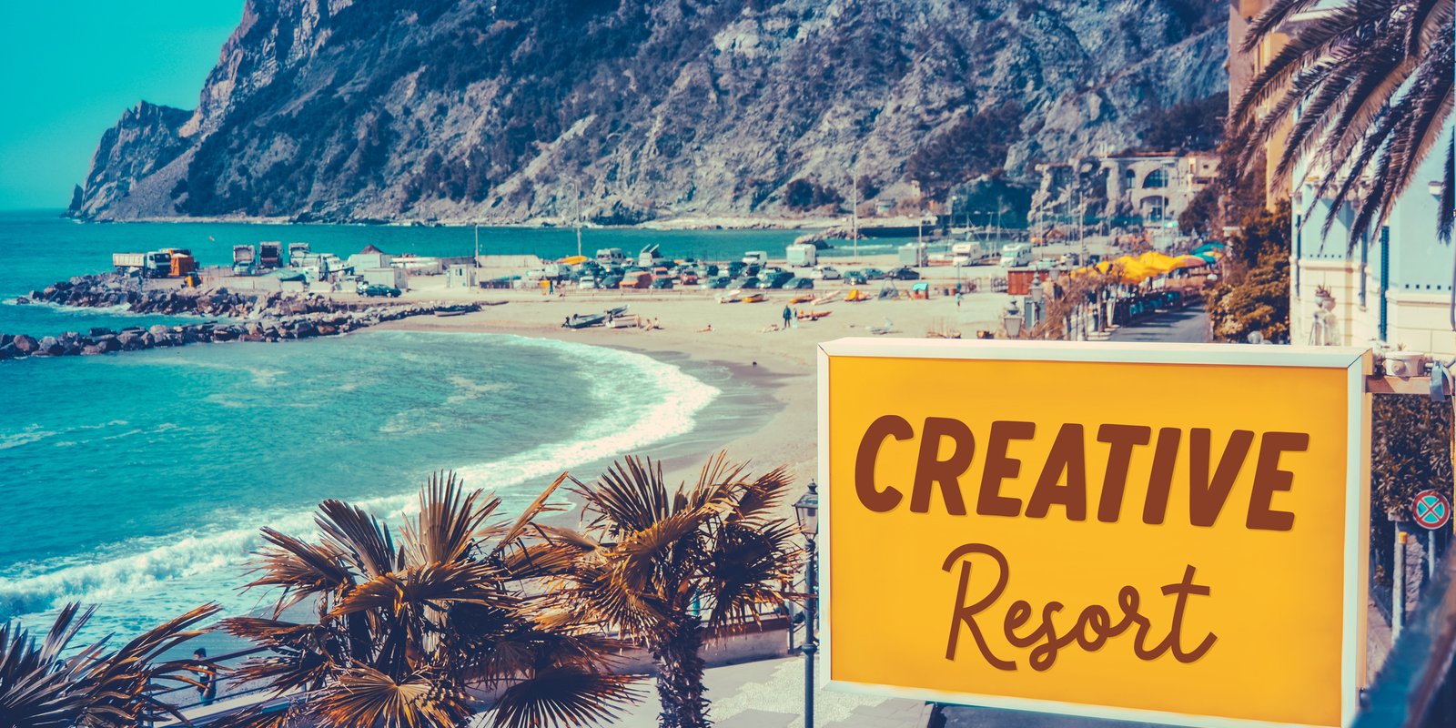 A Creative Resort sign above a beachside town with palm trees